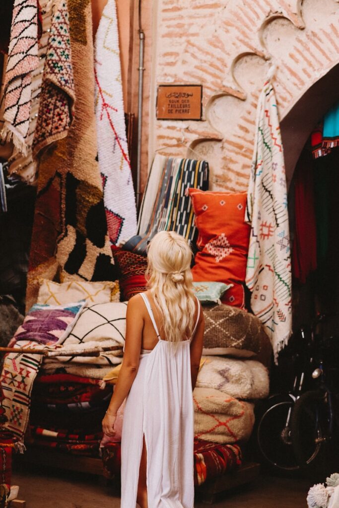 A woman standing in front of a bed covered in blankets